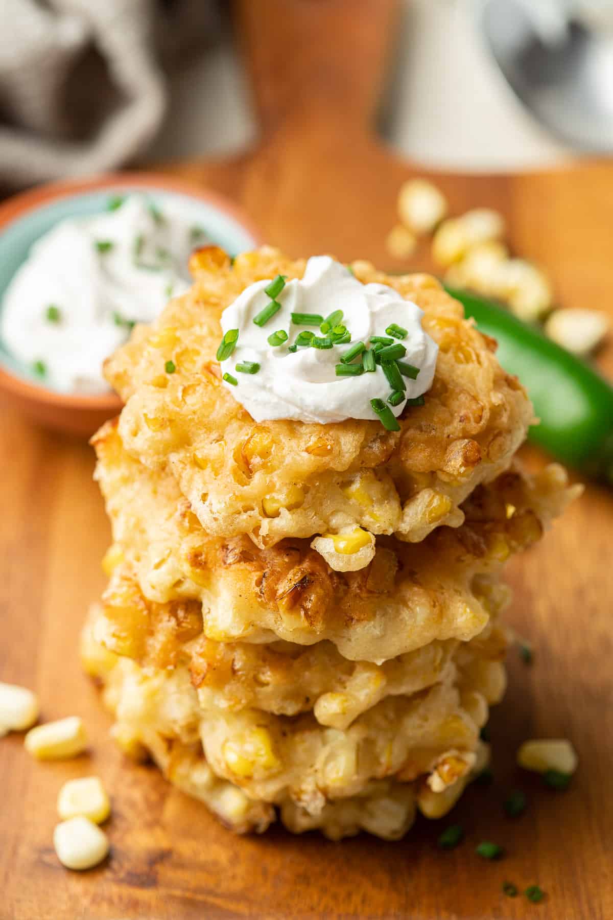 Vegan Corn Fritters in a stack with vegan sour cream and chives on top.
