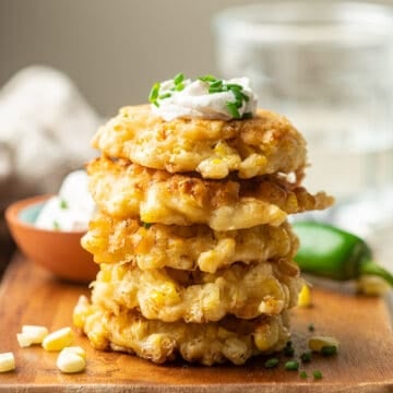 Stack of 5 Vegan Corn Fritters with vegan sour cream on top.