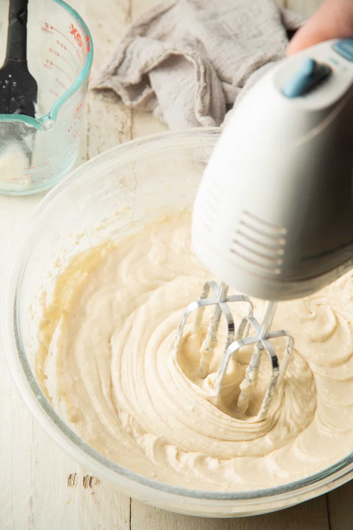 Hand mixing cake batter with an electric mixer.