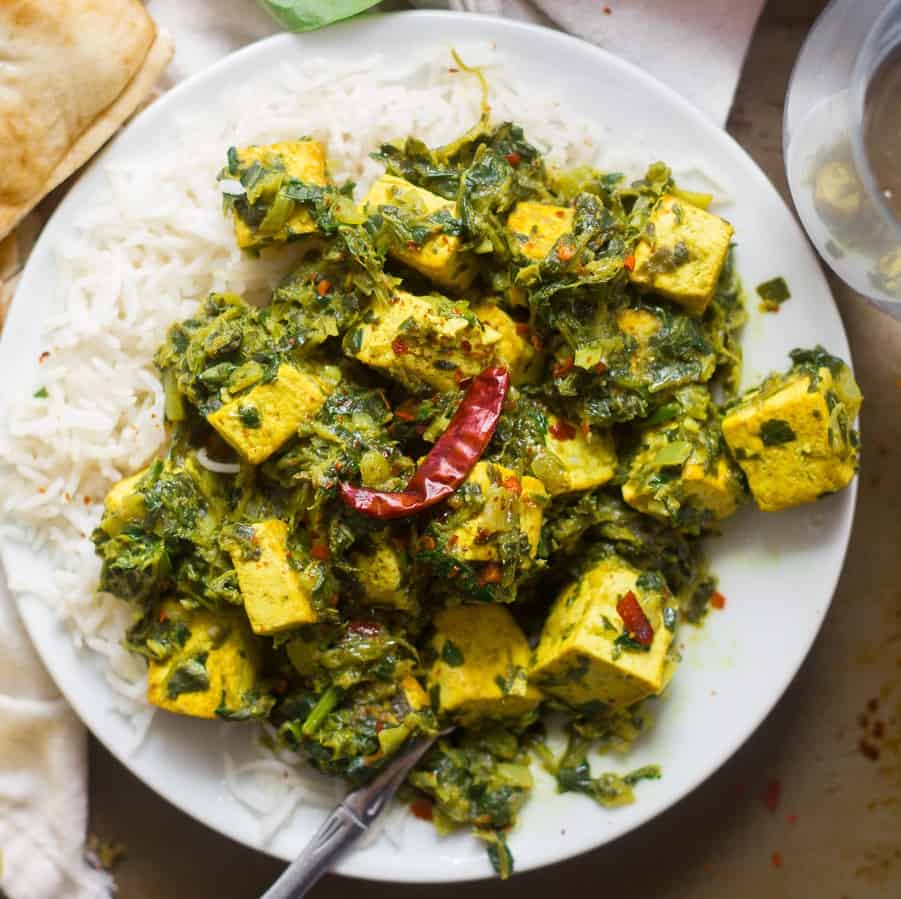 Plate of vegan saag paneer and rice with fork.