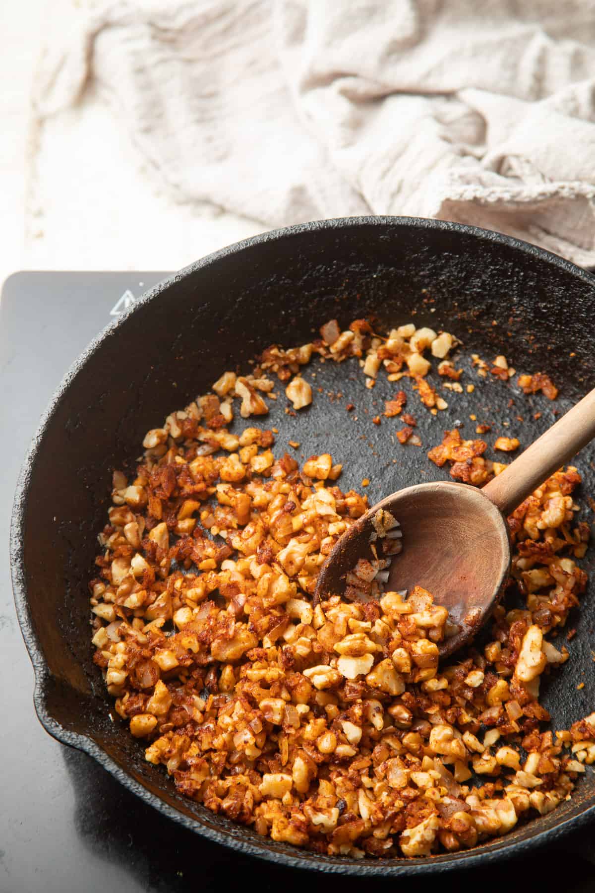 Walnuts cooking in a skillet with onions and spices.