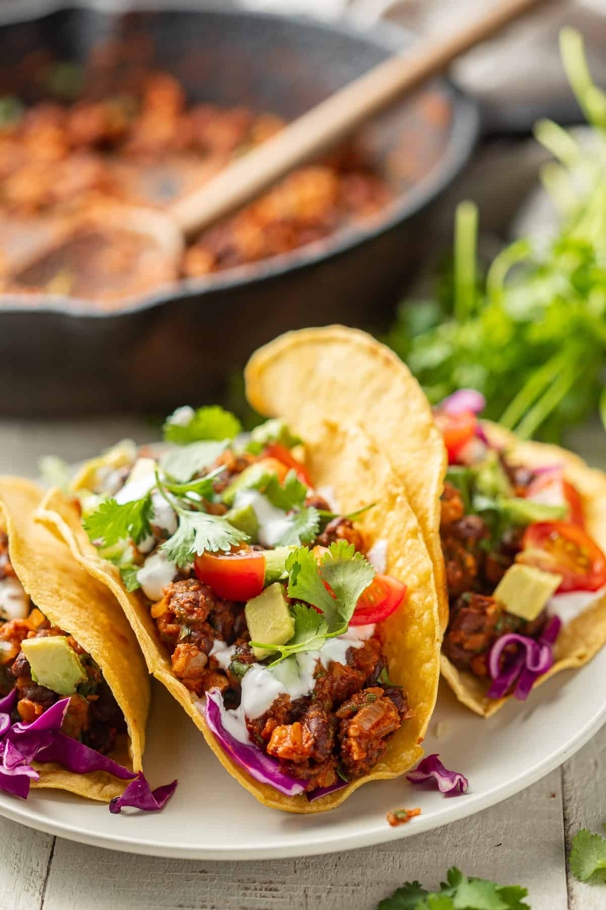 Three Vegan Tacos on a plate with skillet in the background.