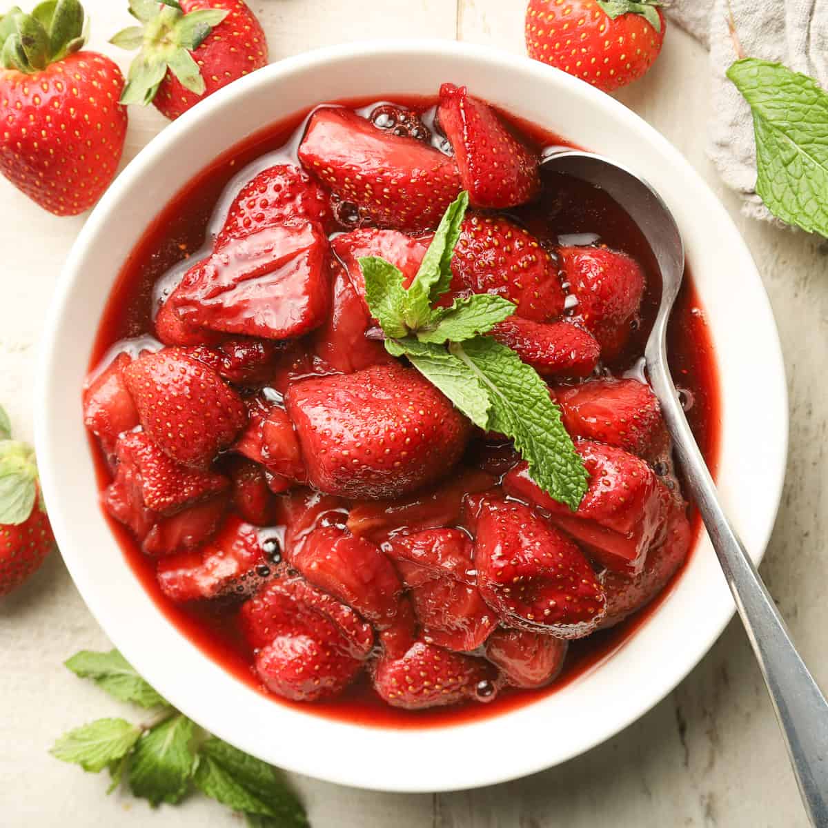 Bowl of Roasted Strawberries with mint leaves on top.