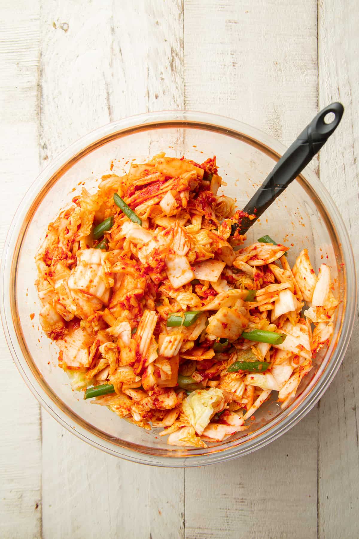 Ingredients for Vegan Kimchi in a glass bowl with spatula.