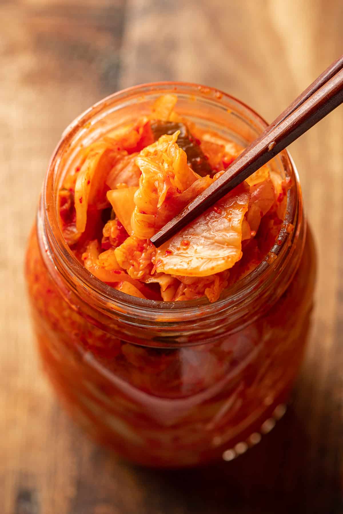 Chopsticks picking up Vegan Kimchi from a jar.