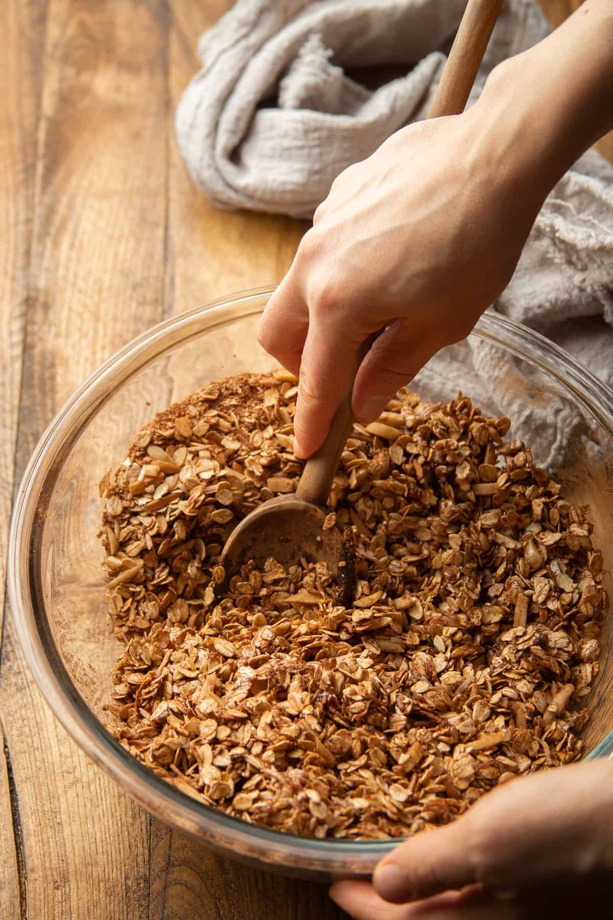 Hand stirring Chocolate Granola ingredients together in a bowl.