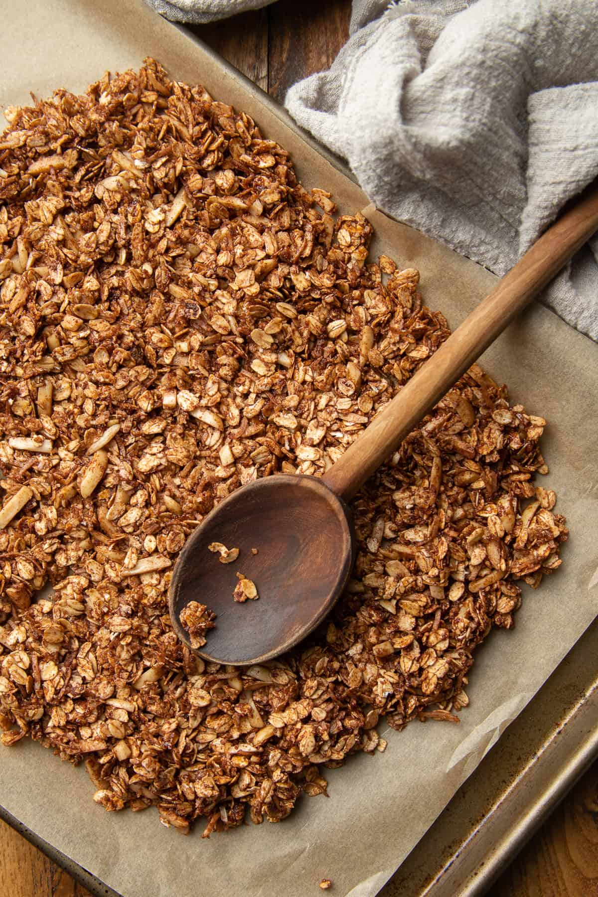 Chocolate Granola on a baking sheet with wooden spoon.