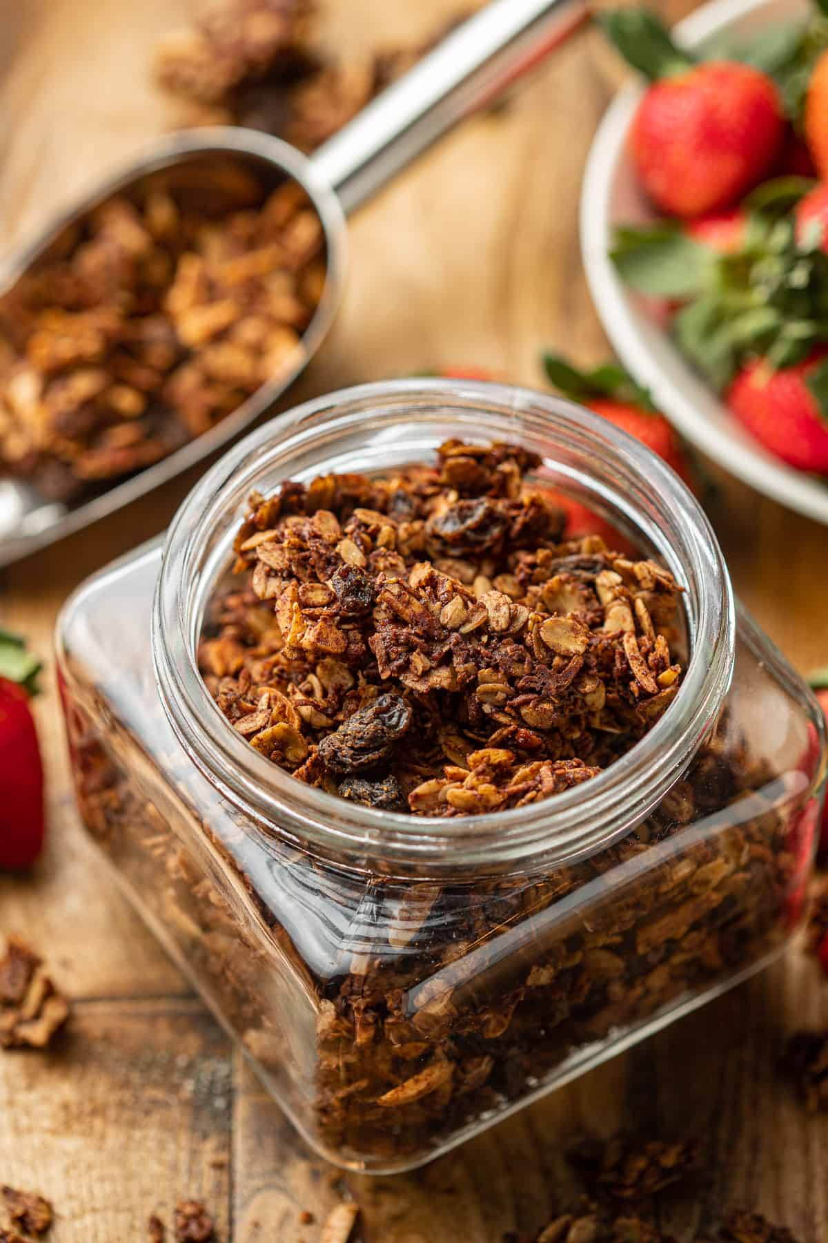 Canister of Chocolate Granola with scoop in the background.