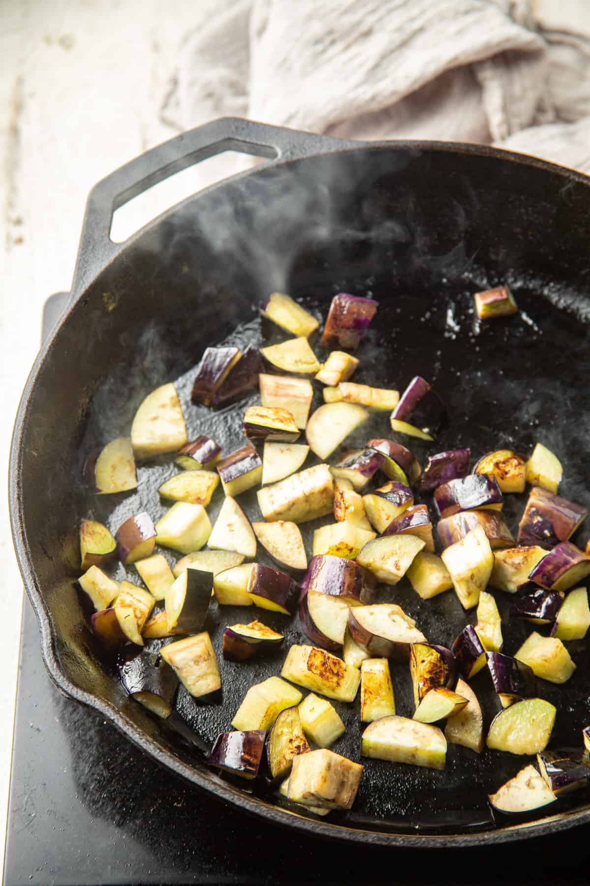 Diced eggplant cooking in a skillet.