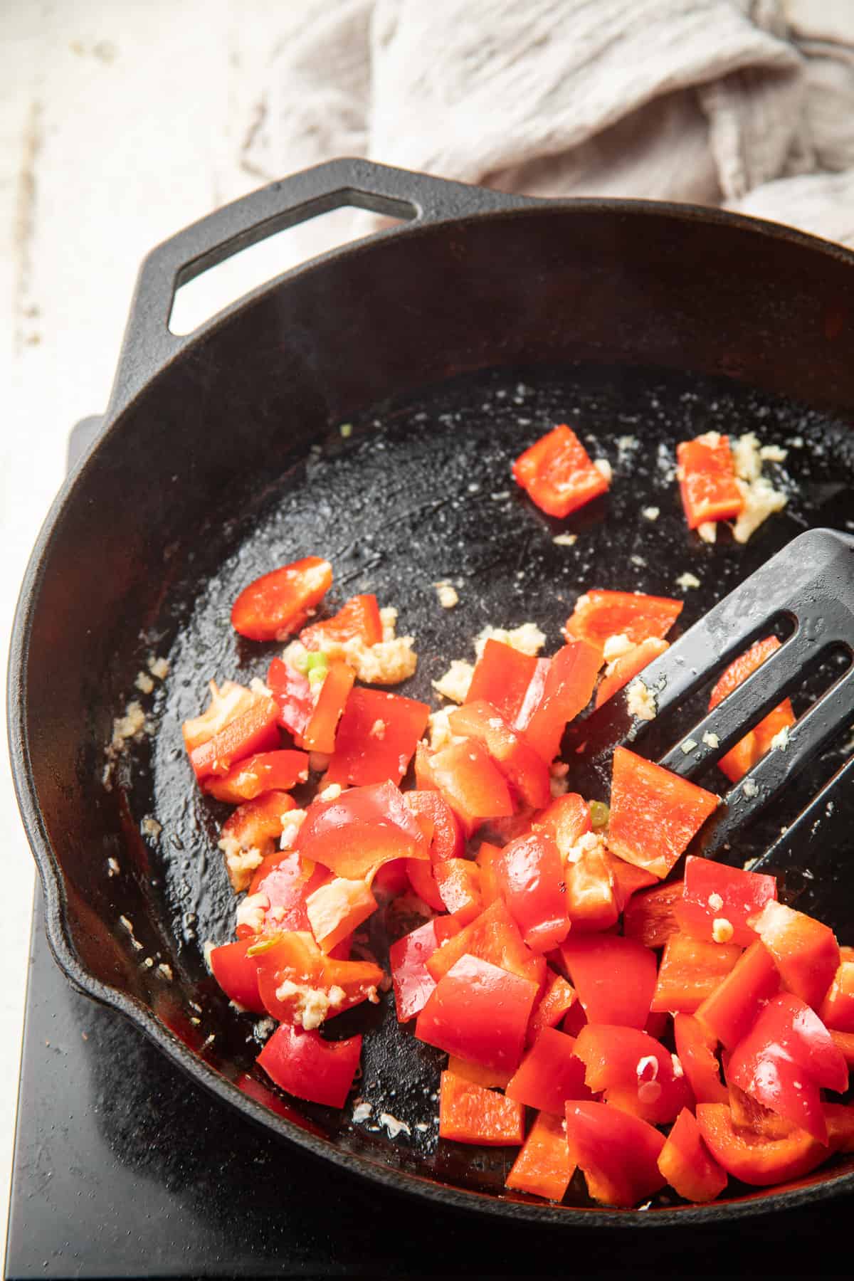Red peppers, garlic, ginger and scallions cooking in a skillet.