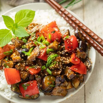 Eggplant Stir Fry on a plate with rice and chopsticks.