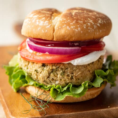 Falafel Burger on a bun with lettuce, tomato, onion slices and vegan yogurt.