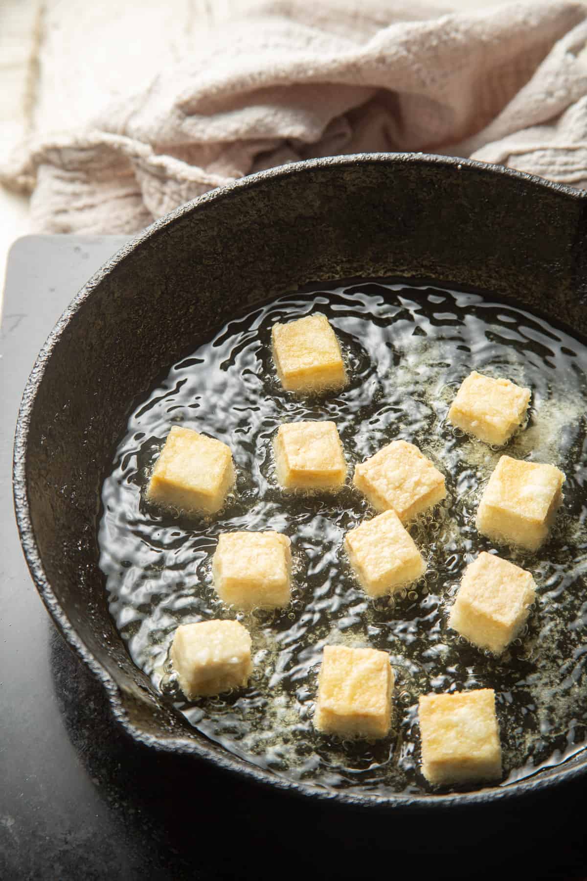 Tofu cubes frying in a skillet.