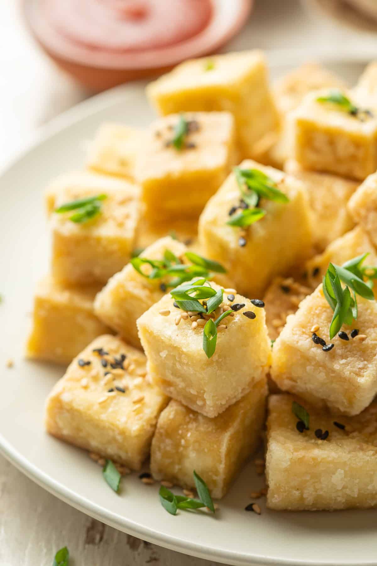 Plate of Fried Tofu cubes topped with chives and sesame seeds.