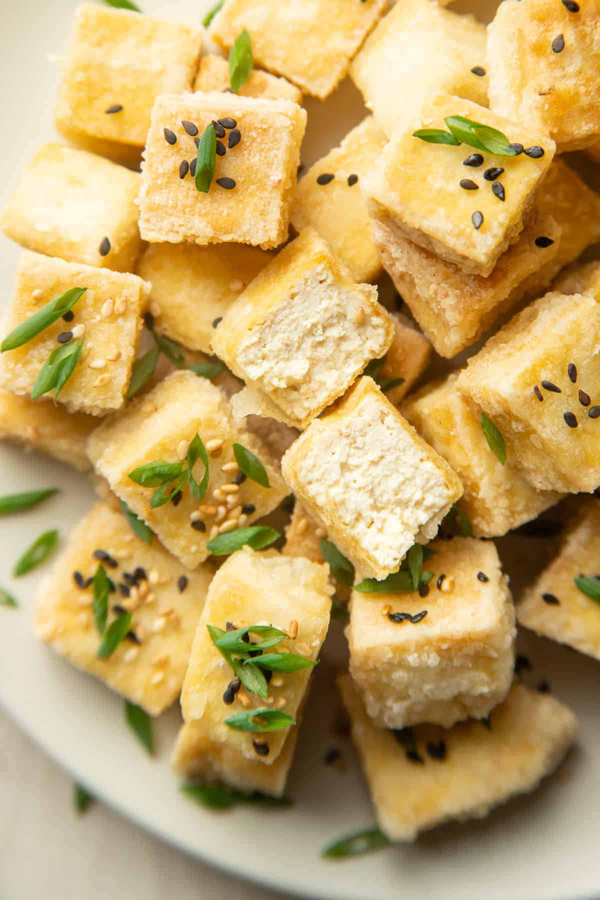 Plate of Fried Tofu cubes with one of them cut in half.