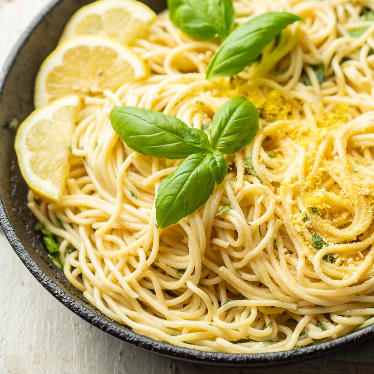 Close up of Lemon Pasta in a skillet with lemon slices and fresh basil.