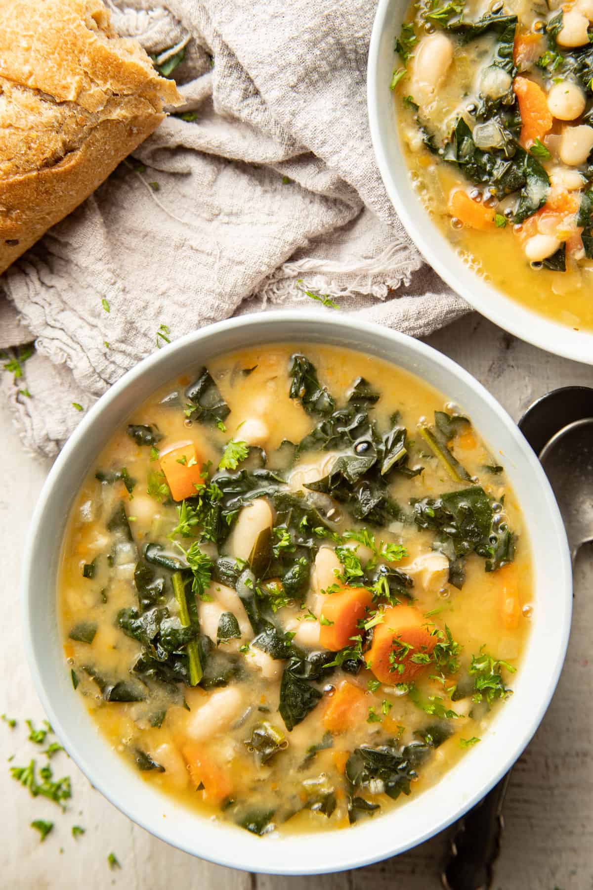 Two bowls of Tuscan Kale Soup and a baguette.