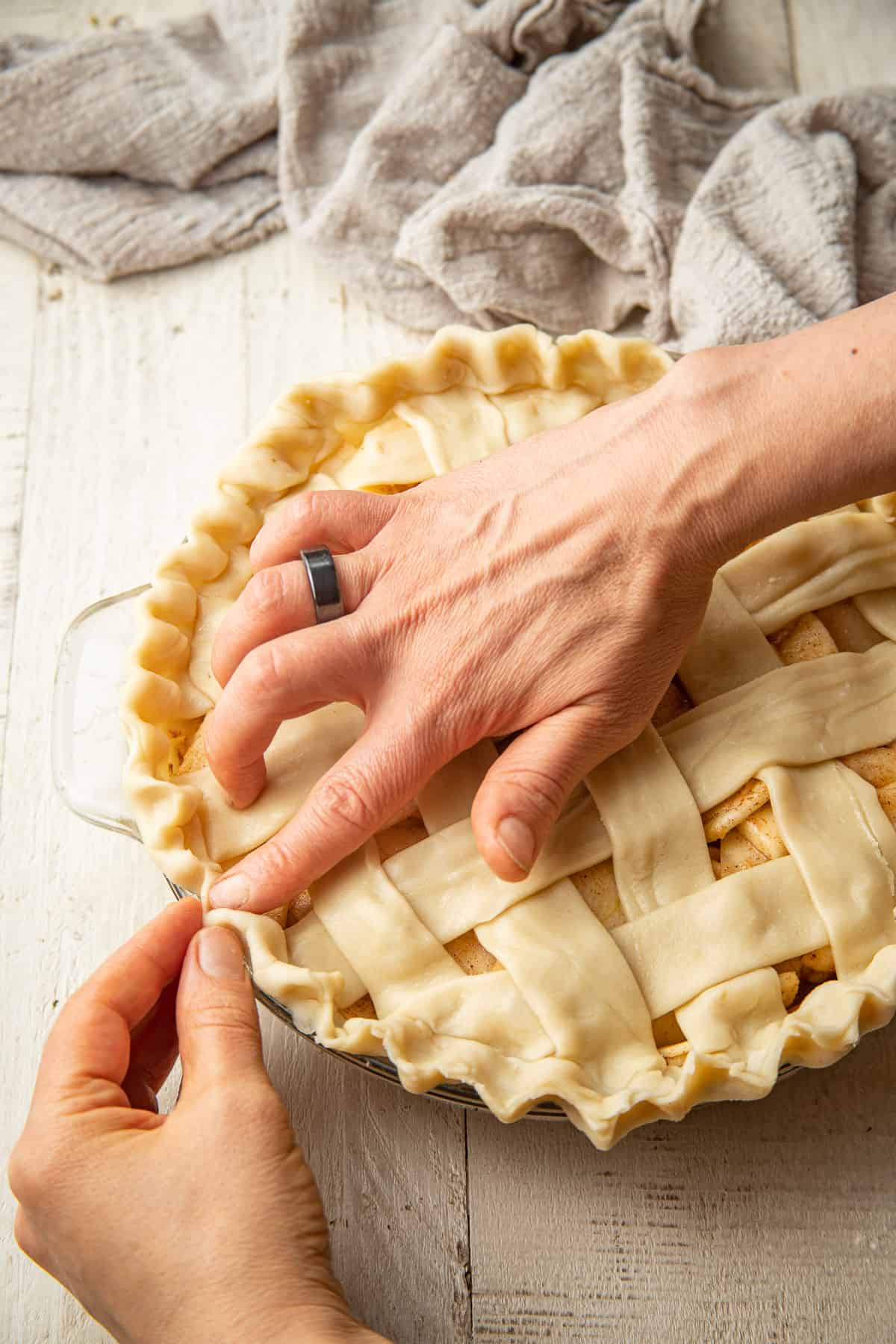 Hands crimping a pie crust.