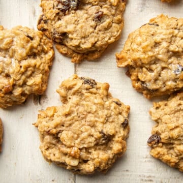 Vegan Oatmeal Raisin Cookies arranged on a white wooden surface.