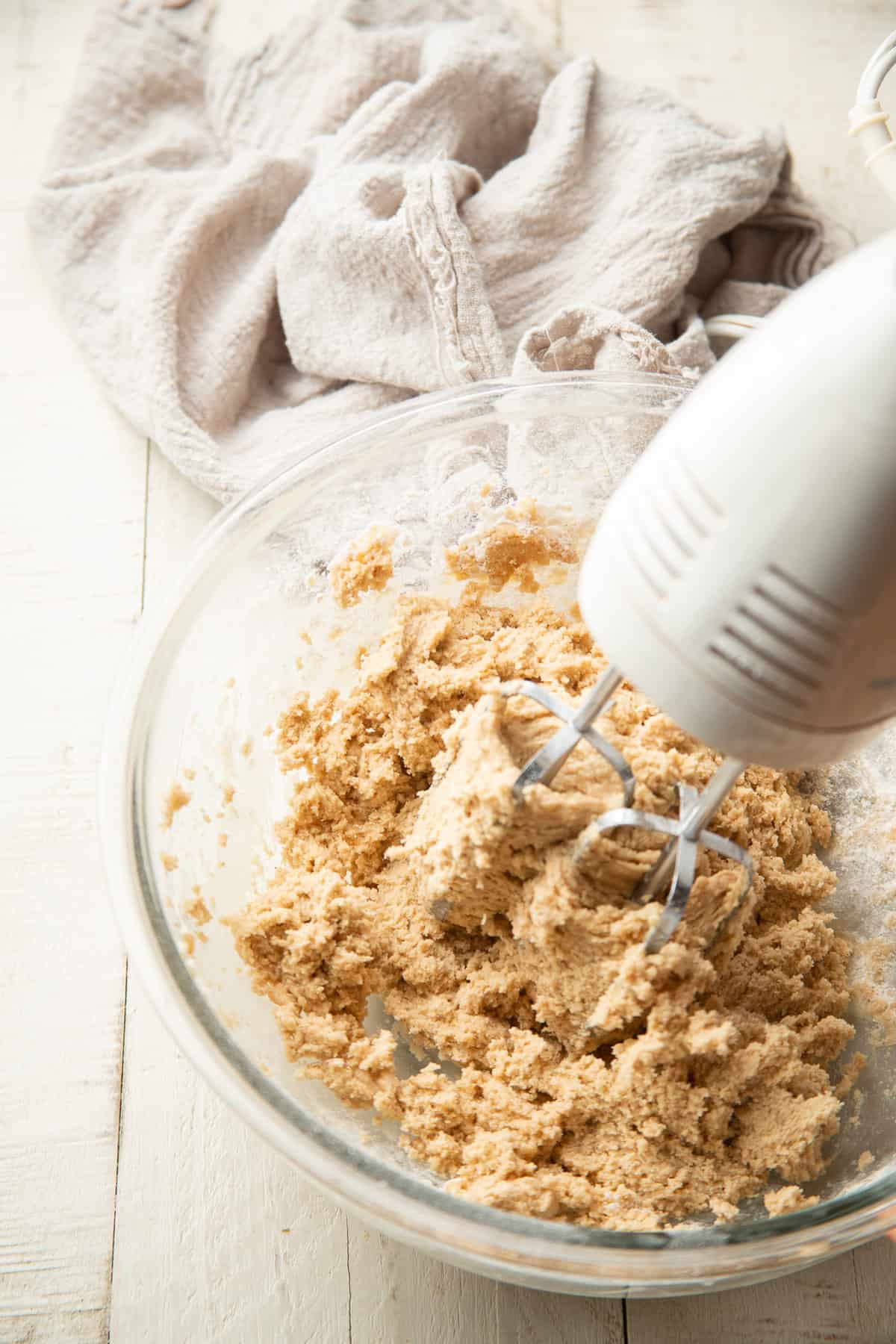Electric mixer beating cookie dough together in a bowl.