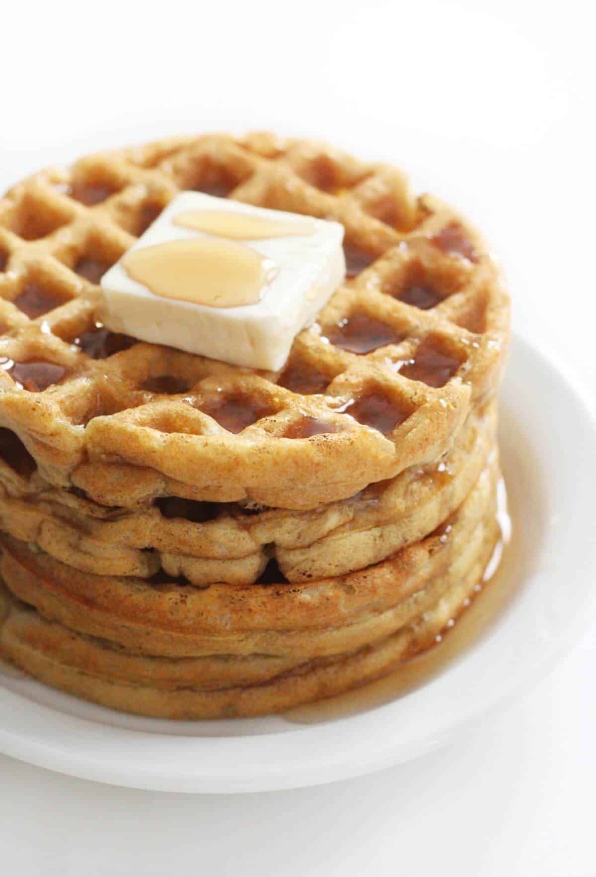 Stack of vegan waffles with butter and syrup on top.