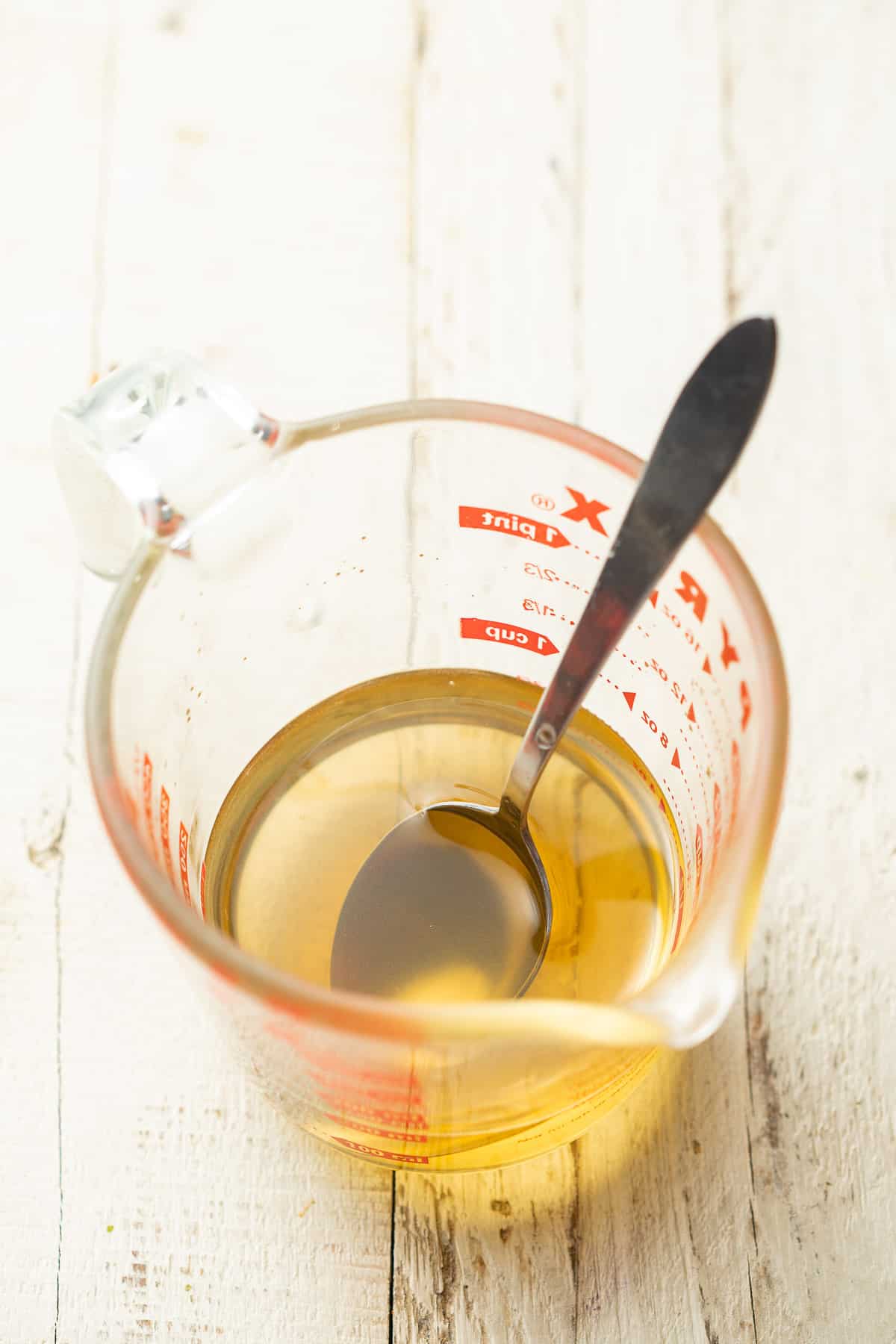 Liquid measuring cup with a spoon and simple syrup inside.