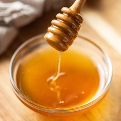 Honey dipper drizzling vegan honey into a bowl.
