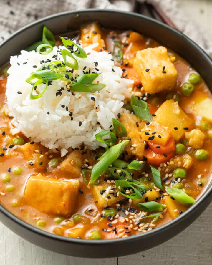 Bowl of Vegan Japanese Curry with rice, scallions and sesame seeds.