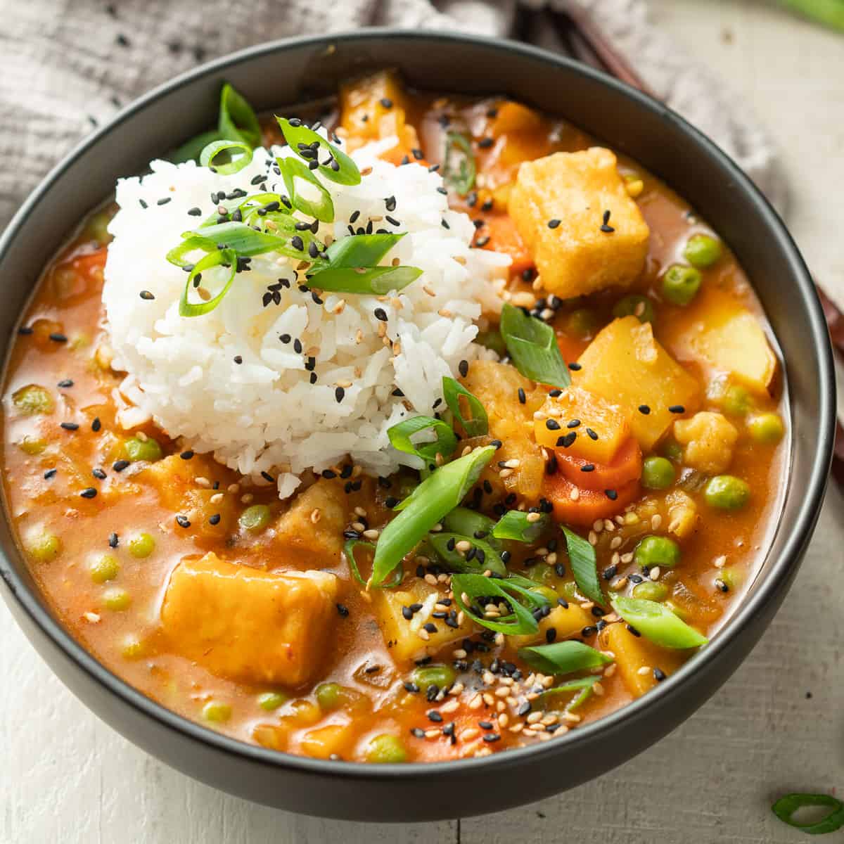 Bowl of Vegan Japanese Curry with rice, scallions and sesame seeds.
