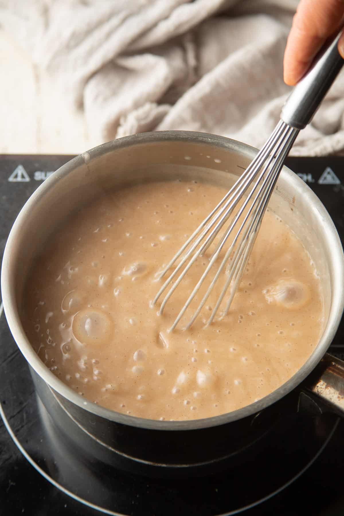 Maple pudding simmering in a saucepan with whisk.