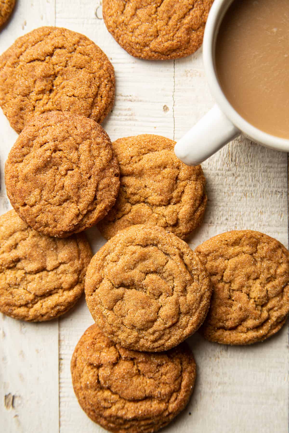 Vegan Ginger Molasses Cookies and coffee cup on a white wooden surface.