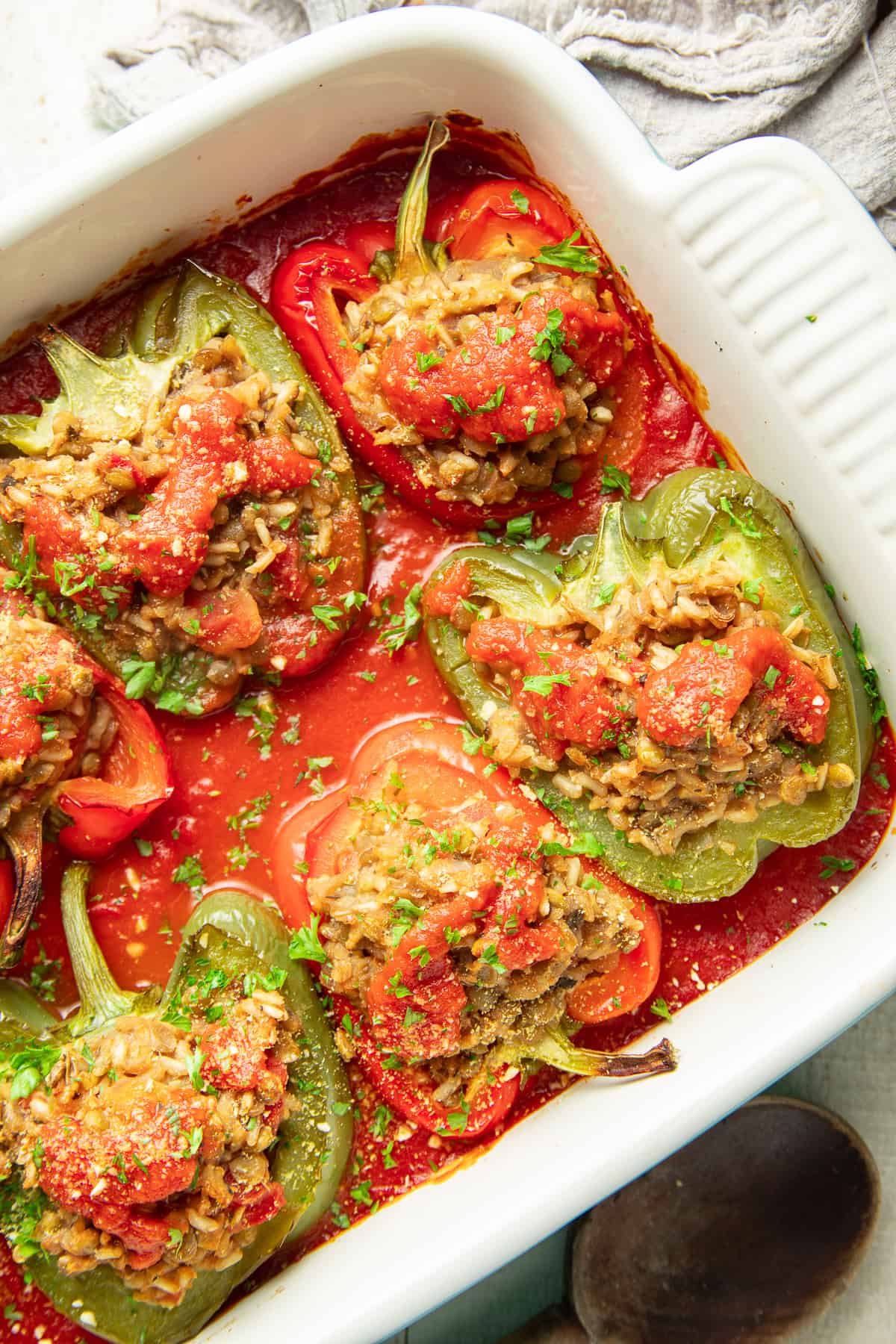 Baking dish filled with Vegan Stuffed Peppers with a spoon on the side.