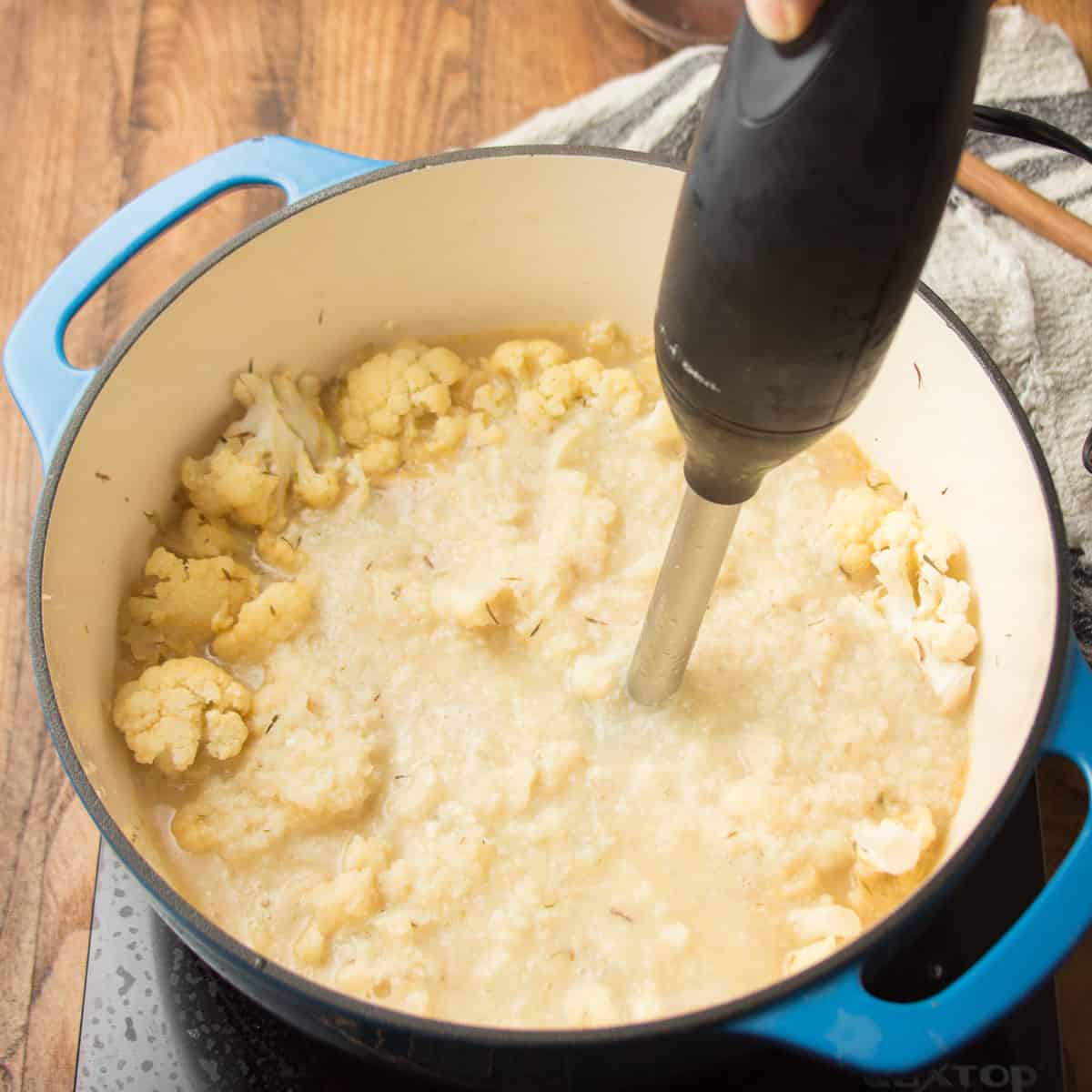 Pot of Vegan Cauliflower Soup being blended with an immersion blender.
