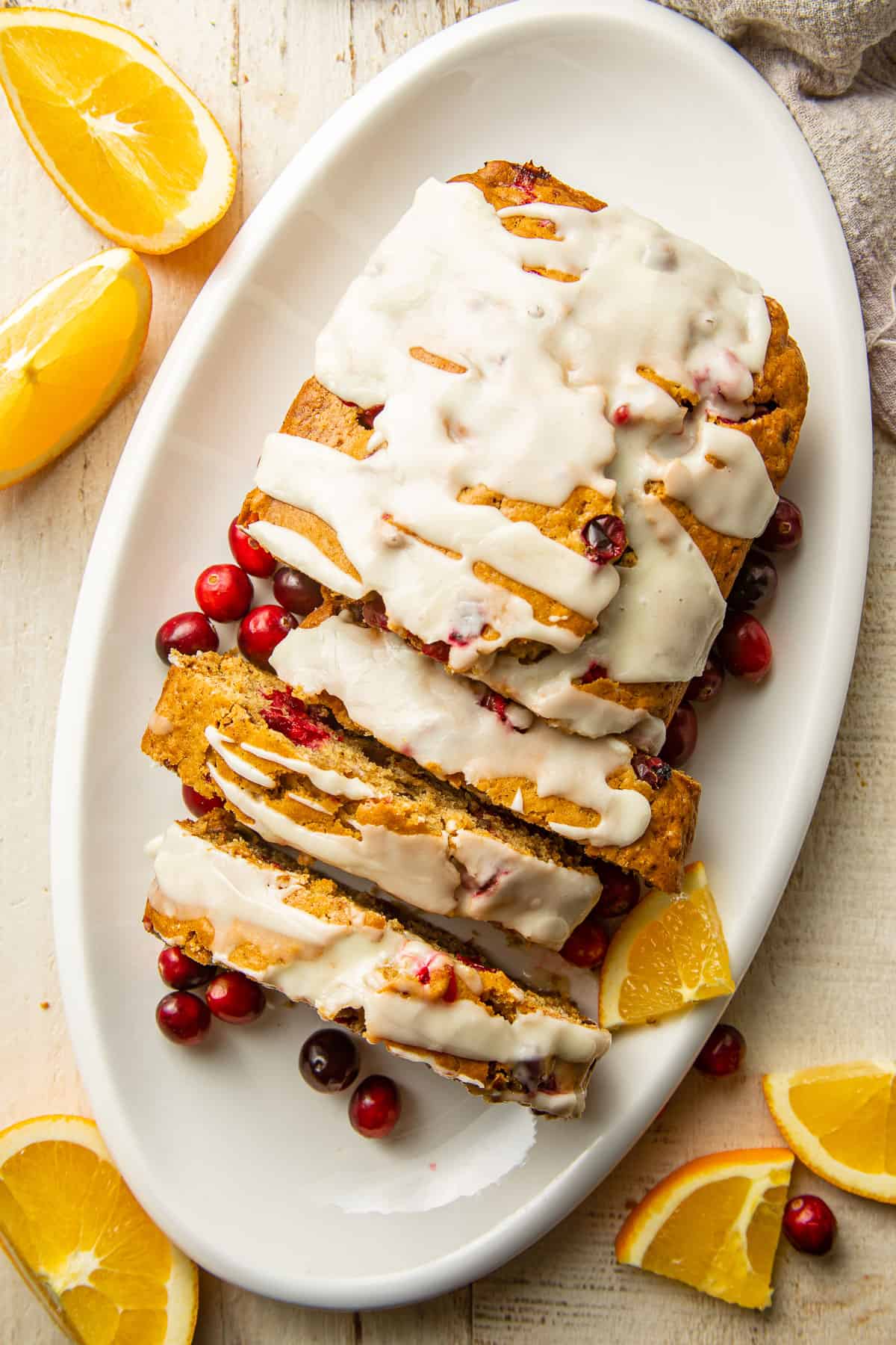 Overhead view of a loaf of Vegan Cranberry Bread with orange slices and fresh cranberries.