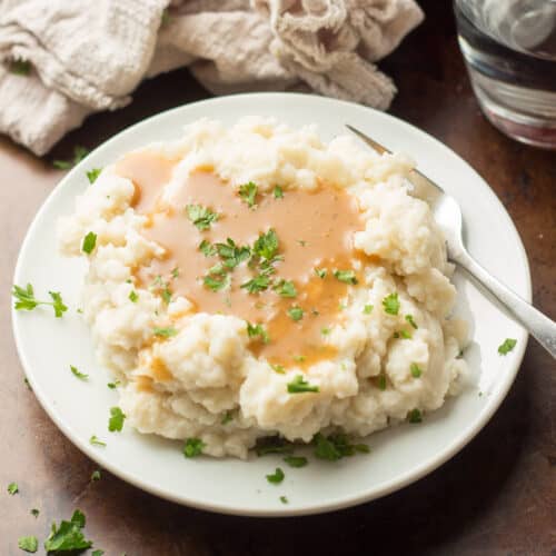 Plate of mashed potatoes covered in vegan gravy.