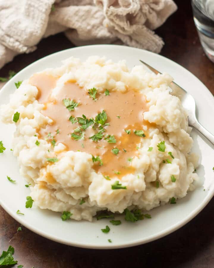 Plate of mashed potatoes covered in vegan gravy.