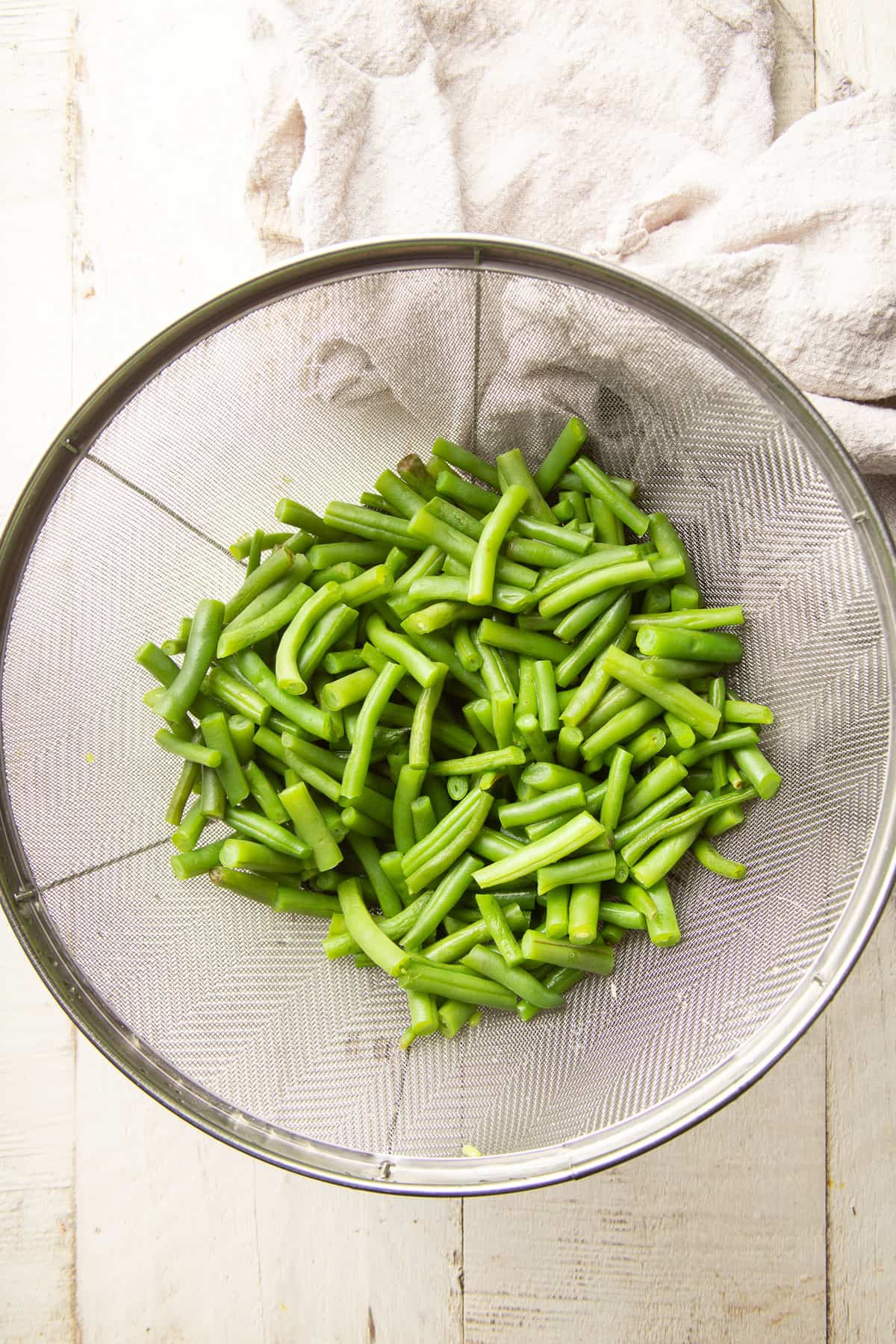 Cooked green beans in a colander.