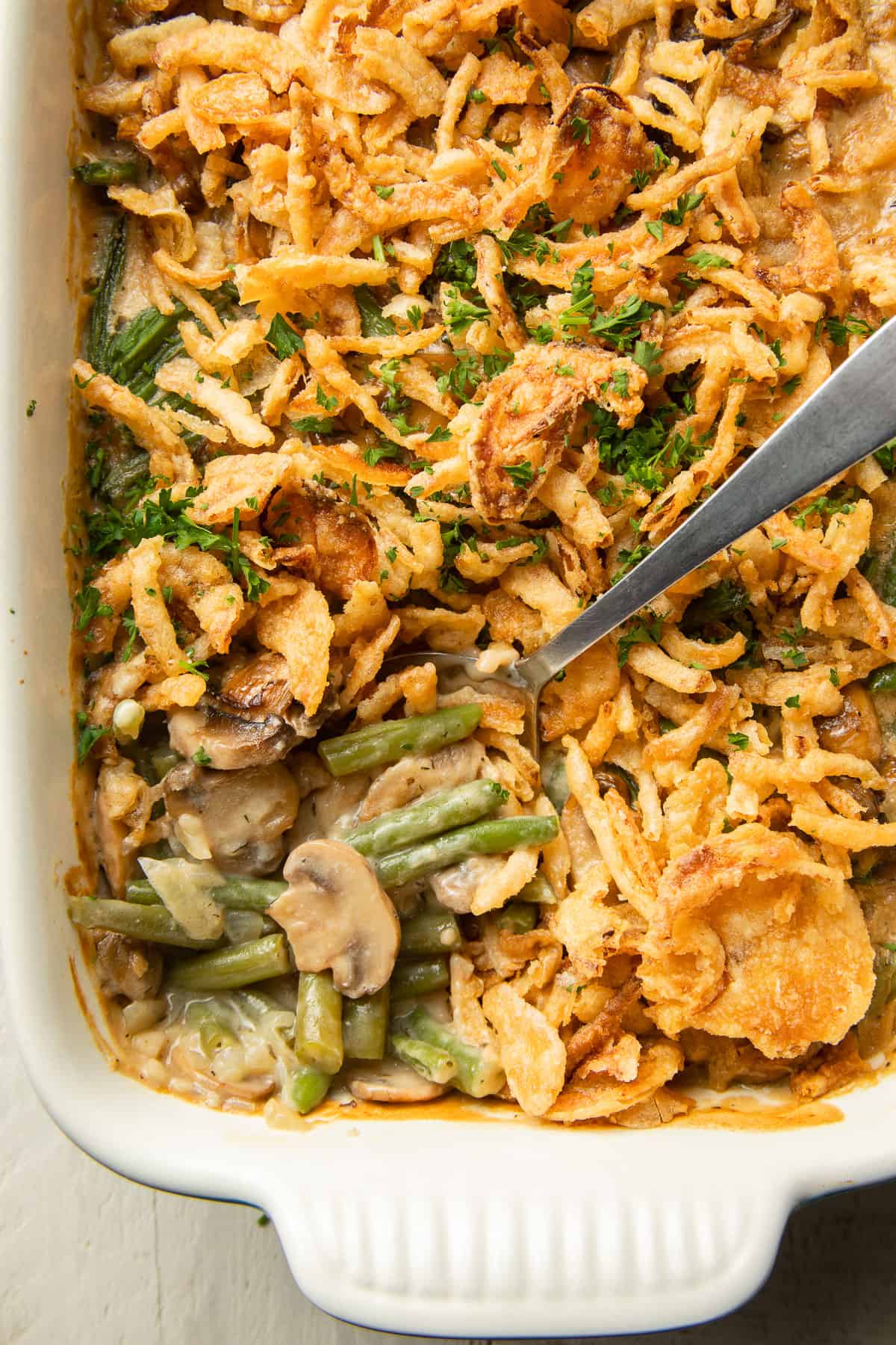 Overhead view of casserole dish of Vegan Green Bean Casserole with serving spoon.