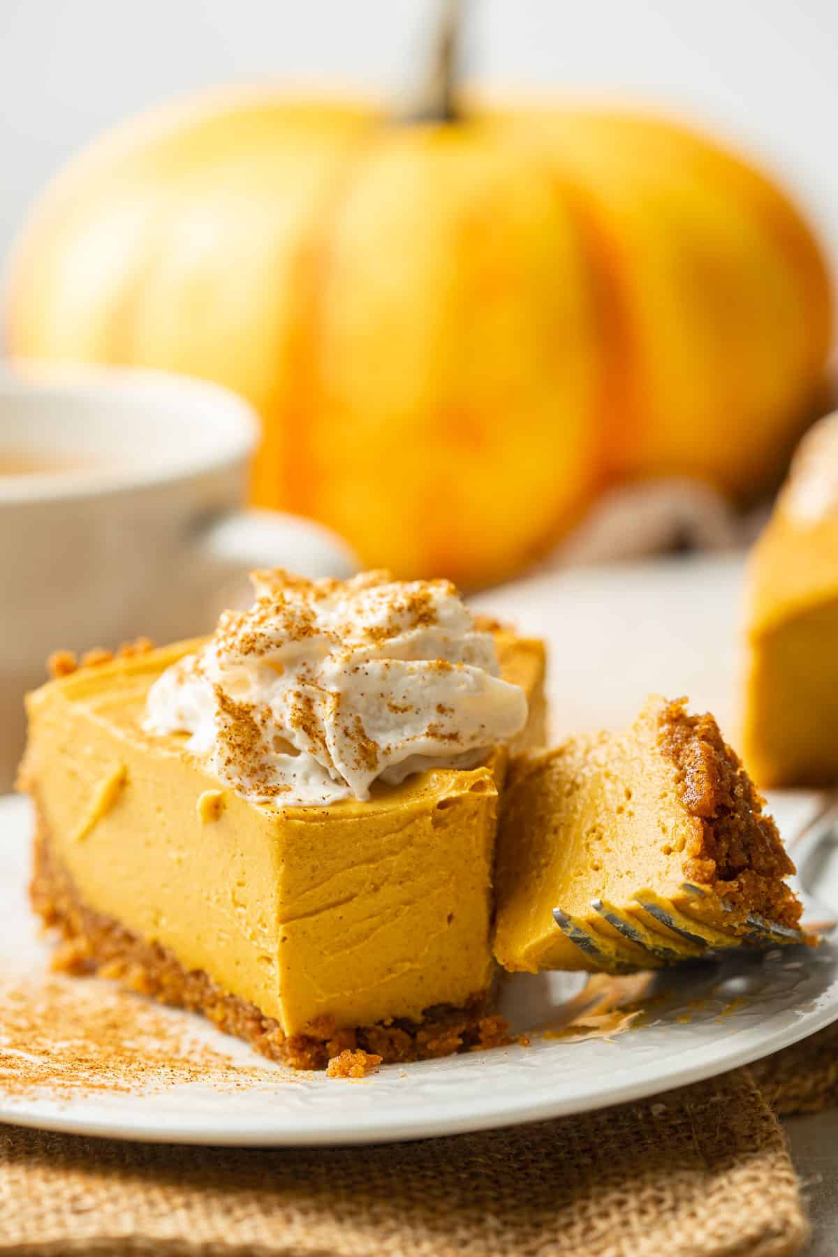 Slice of Vegan Pumpkin Cheesecake on a dish with the tip cut off and resting on a fork.
