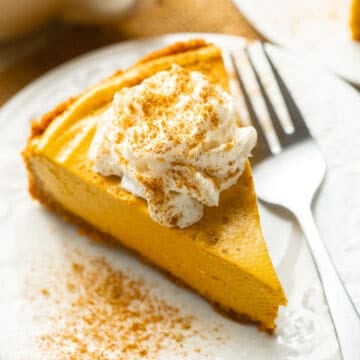 Slice of Vegan Pumpkin Cheesecake topped with whipped cream.