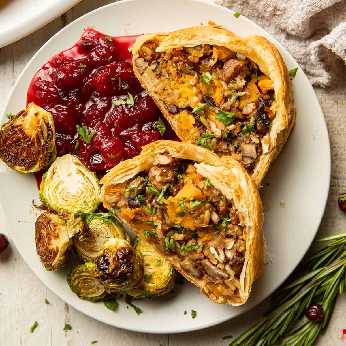 Plate with two slices of Vegetable Wellington, roasted Brussels sprouts and cranberry sauce.