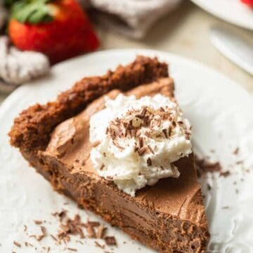 Slice of Vegan Chocolate Pie on a plate with whipped cream and chocolate shavings on top.