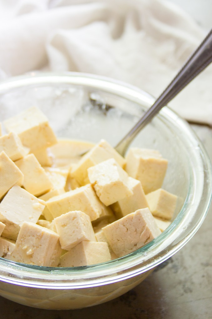 Tofu feta cubes in a bowl with spoon.