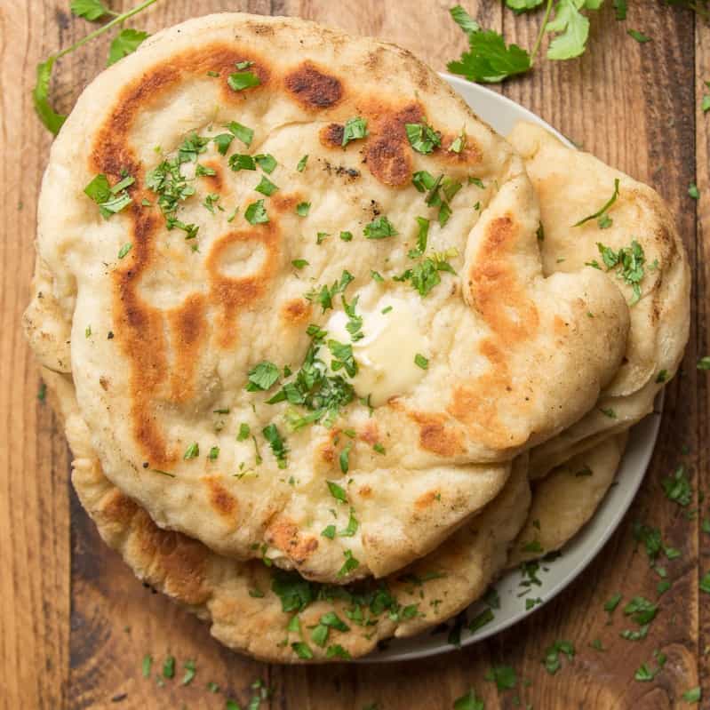 Stack of Vegan Naan on a plate topped with butter and cilantro.
