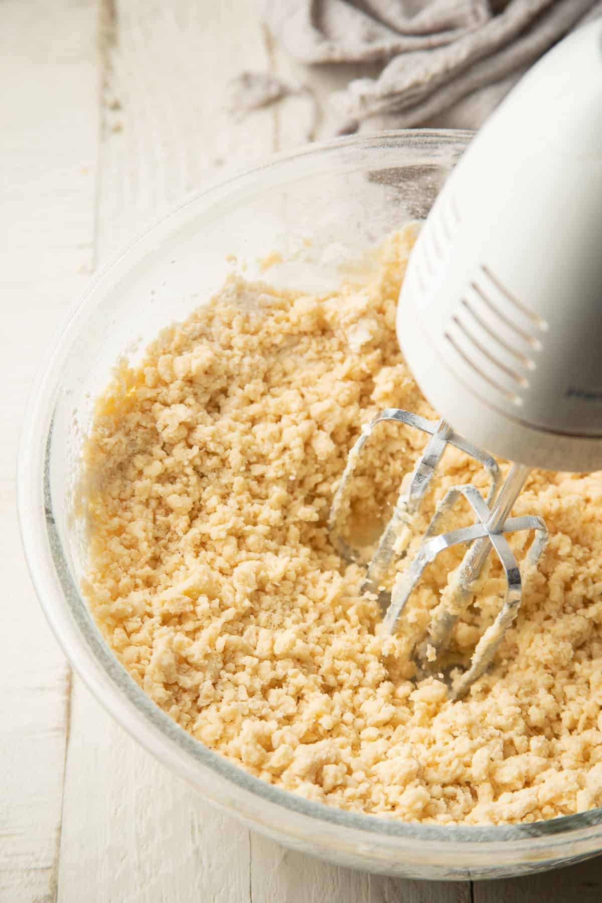 Cookie dough being mixed in a bowl with an electric mixer.