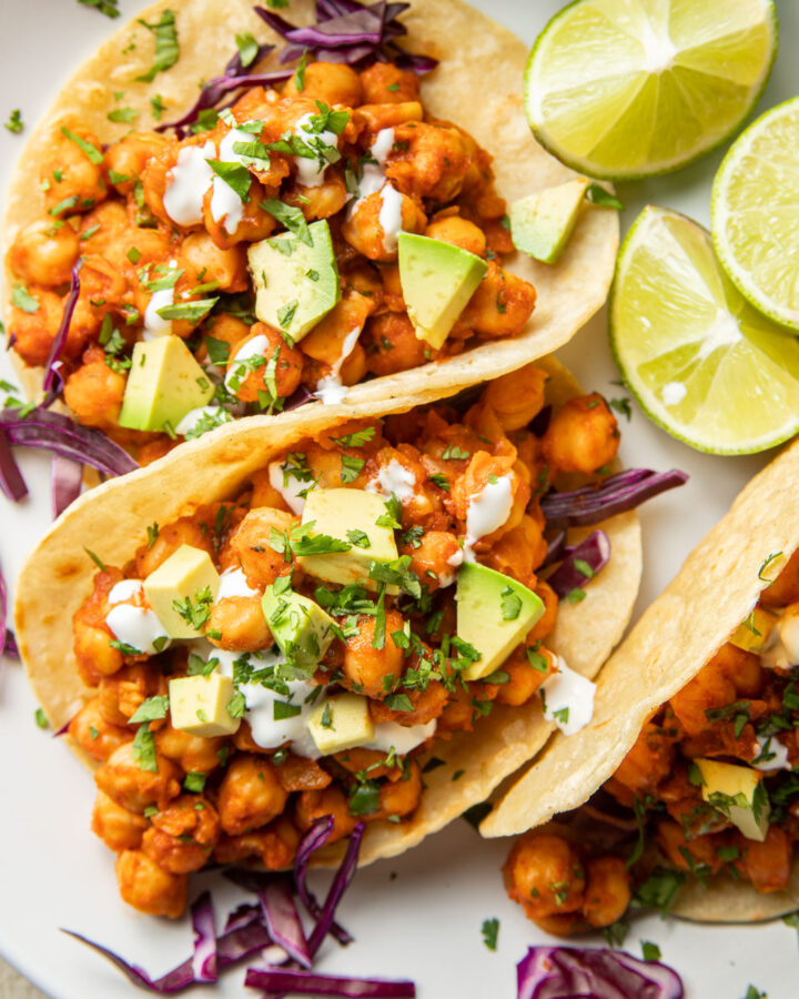 Close up of three Chickpea Tacos on a plate with lime slices.