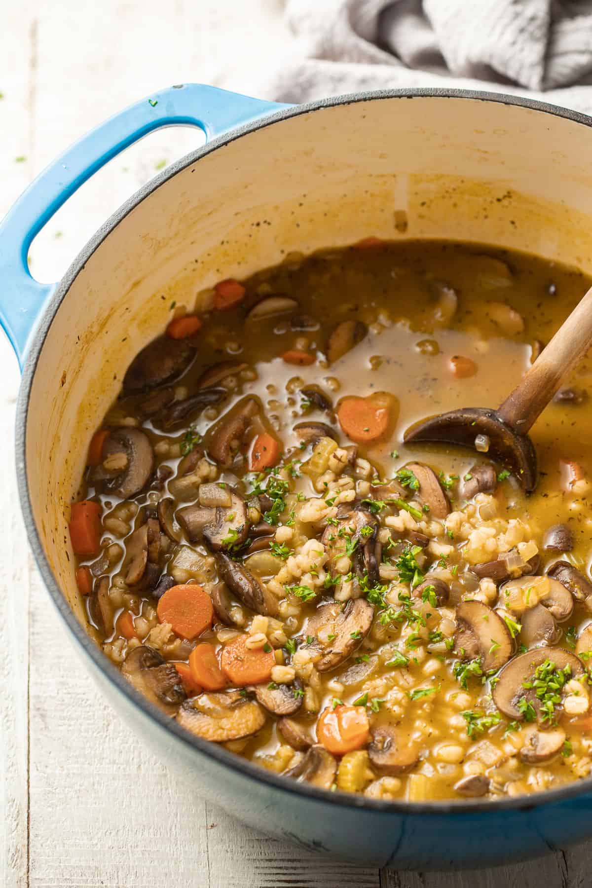 Bowl of mushroom barley soup with wooden spoon.