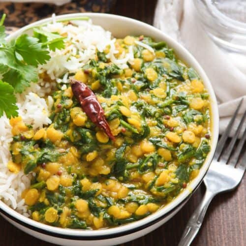 Bowl of Spinach Dal with rice, cilantro, and a dried chile pepper on top.