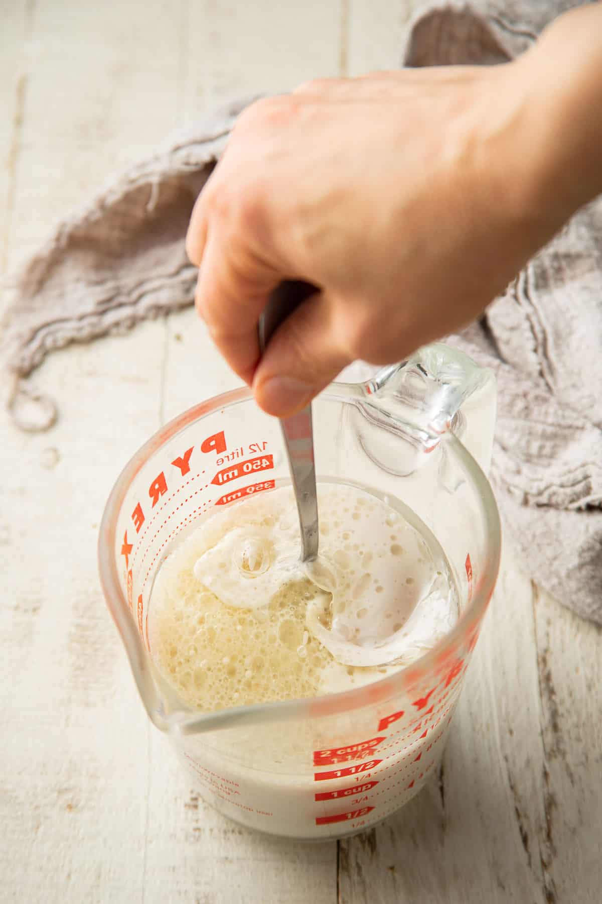 By hand stirring the liquid ingredients for the pancake batter together in a liquid measuring cup.