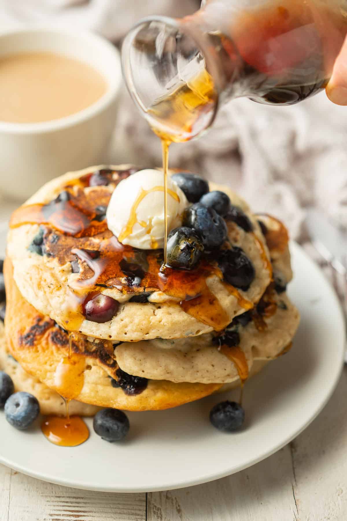 Syrup drizzled over a stack of vegan blueberry pancakes.